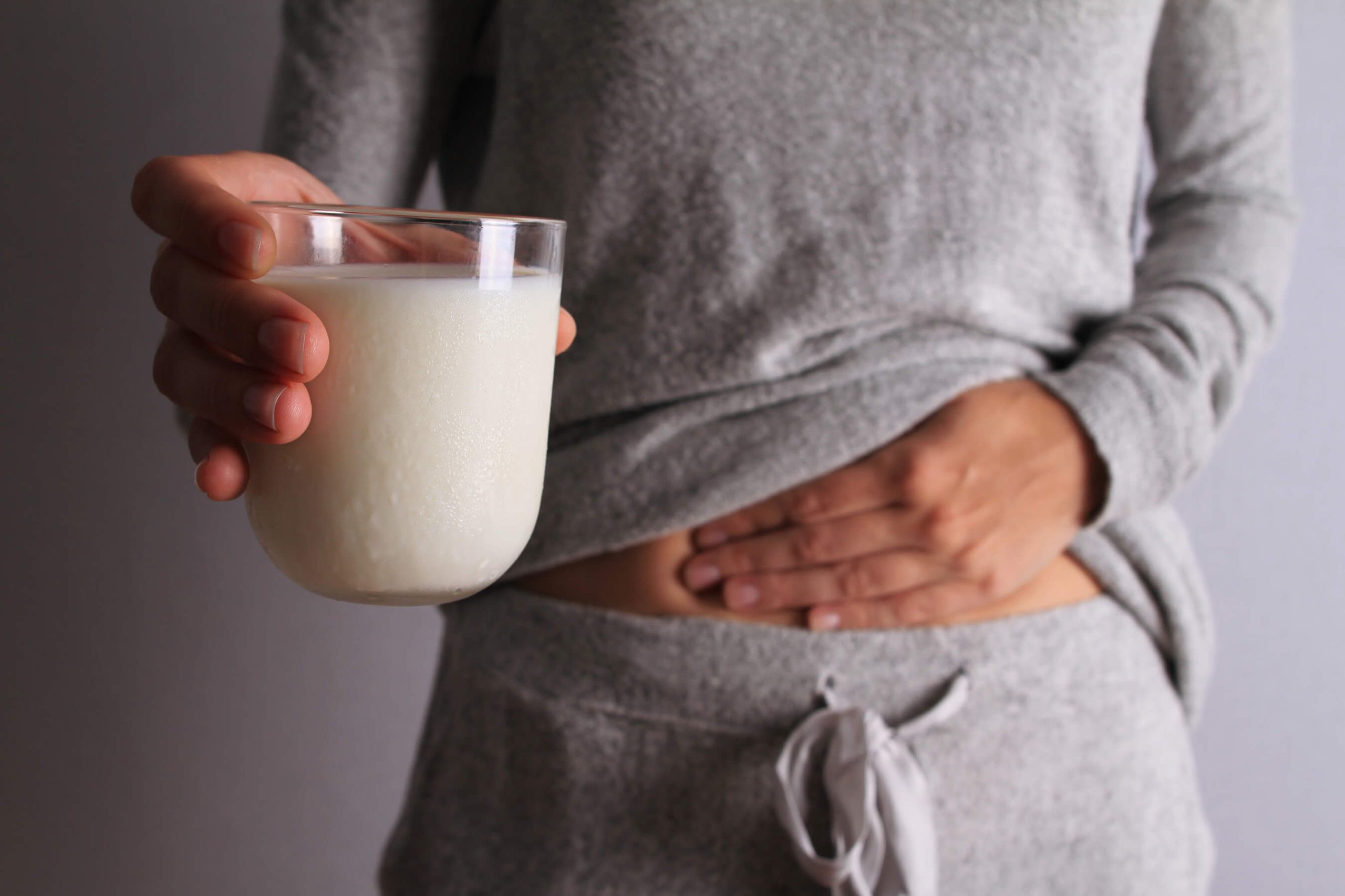 Woman with stomach pain holding a glass of milk